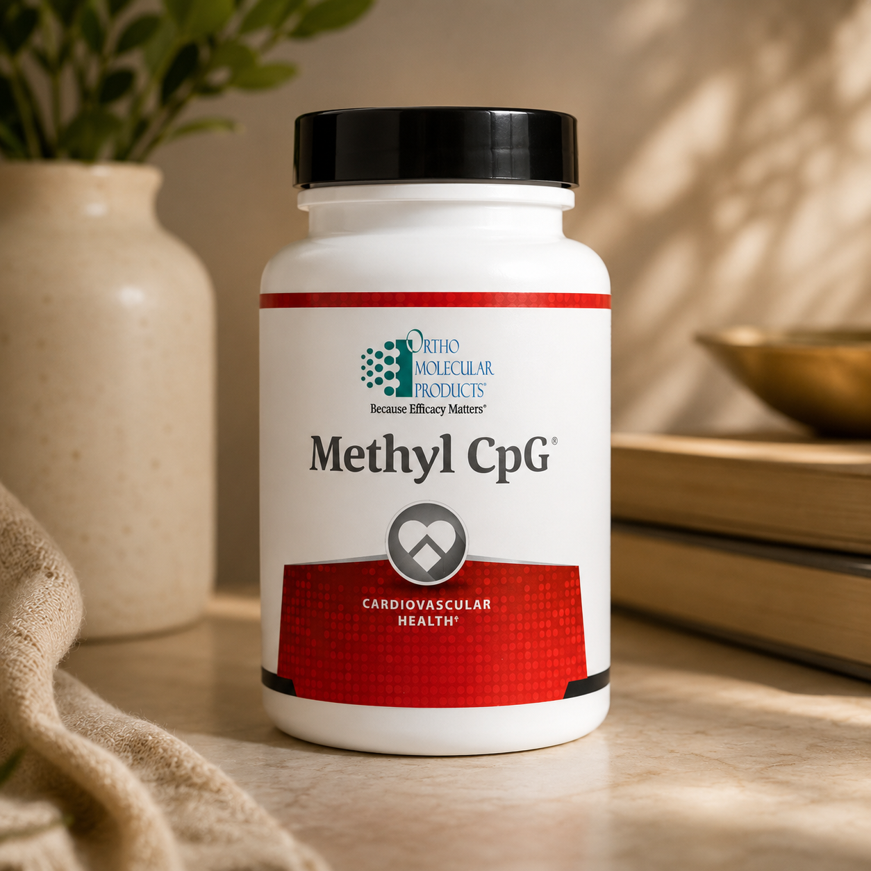 A white supplement bottle labeled  by Ortho Molecular Products, with a black cap, set on a tabletop in a warm, softly lit interior with a vase, books, and a bowl in the background.